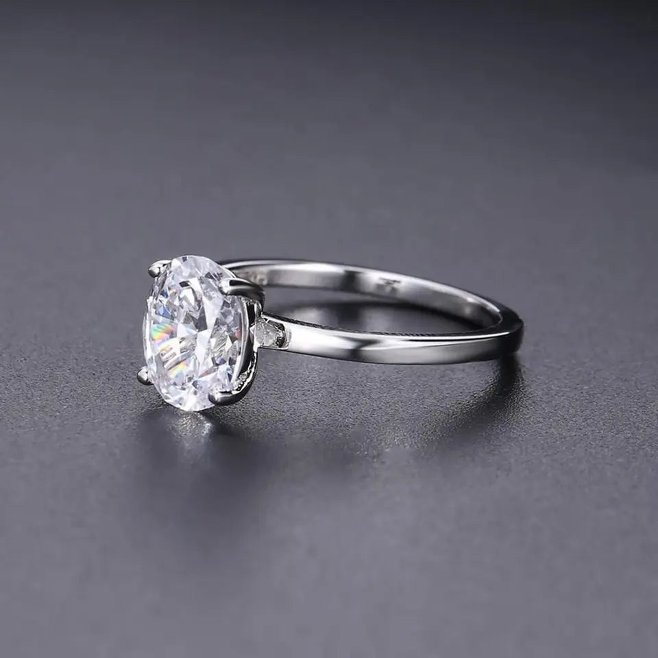 A substantial 3.00ct oval moissanite takes center stage in this minimalist sterling silver engagement ring.