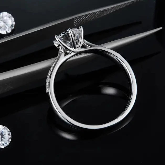 A stunning engagement ring featuring a dazzling moissanite center stone and a pave band of smaller moissanites, set in polished sterling silver.