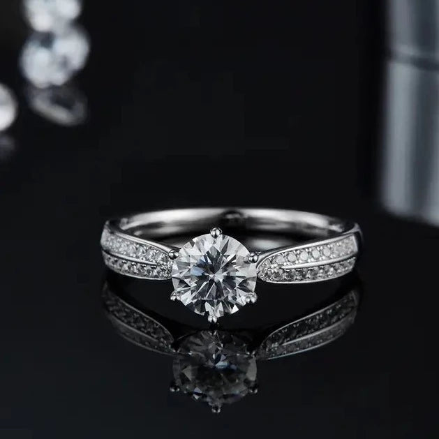 This sterling silver engagement ring features a 1.00ct moissanite center stone, enhanced by a delicate pave setting that adds extra sparkle.