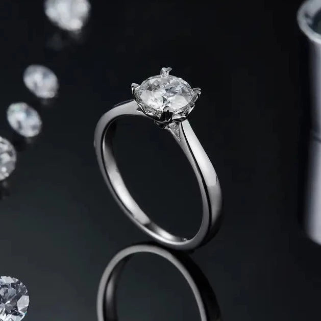 This classic solitaire engagement ring in sterling silver features a stunning 1.00ct moissanite, with heart-shaped claws adding a touch of romance to the design.