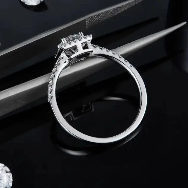 This sterling silver engagement ring features a petite 0.50ct moissanite with a sparkling halo, perfect for a subtle yet elegant look.
