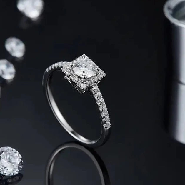 A beautiful sterling silver ring featuring a 0.50ct moissanite center stone, surrounded by a halo of smaller stones, creating a timeless and elegant design.