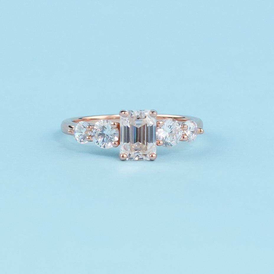 Stunning five-stone engagement ring featuring emerald cut moissanites, set in warm 9ct rose gold for eternal brilliance.