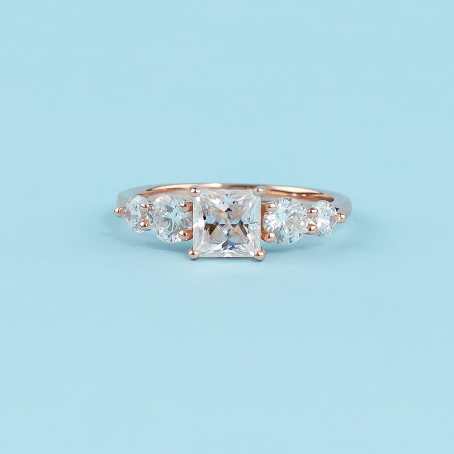 Stunning five-stone engagement ring featuring princess cut moissanites, set in warm 9ct rose gold for eternal brilliance.