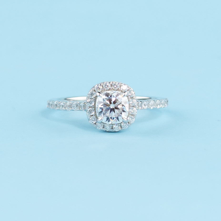 Elegant 9ct white gold engagement ring featuring a cushion cut moissanite encircled by a classic halo setting.