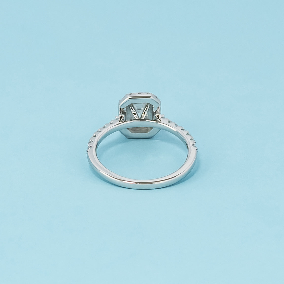 Luxurious 9ct white gold engagement ring with a classic halo design that enhances the brilliance of the emerald cut moissanite.