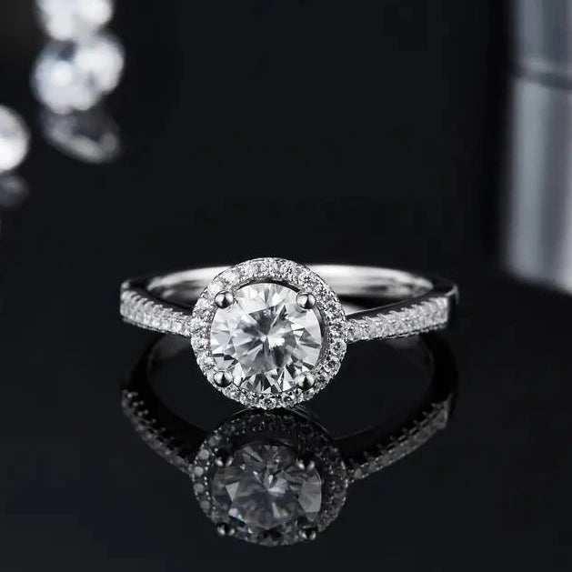 A close-up of a sterling silver engagement ring, highlighting the intricate heart-shaped halo surrounding a dazzling 1.00ct moissanite.