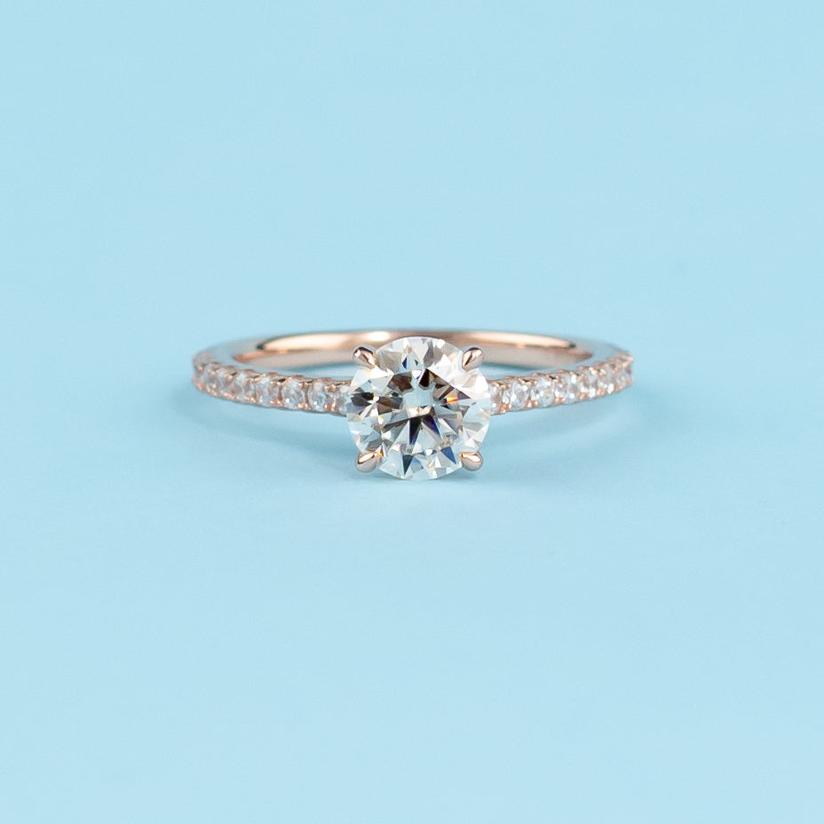 Elegant round brilliant moissanite engagement ring with a hidden halo setting, crafted in warm 9ct rose gold.