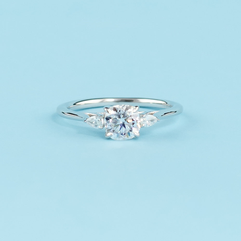 Elegant 9ct white gold engagement ring featuring three sparkling cushion cut moissanites in a classic trilogy design.