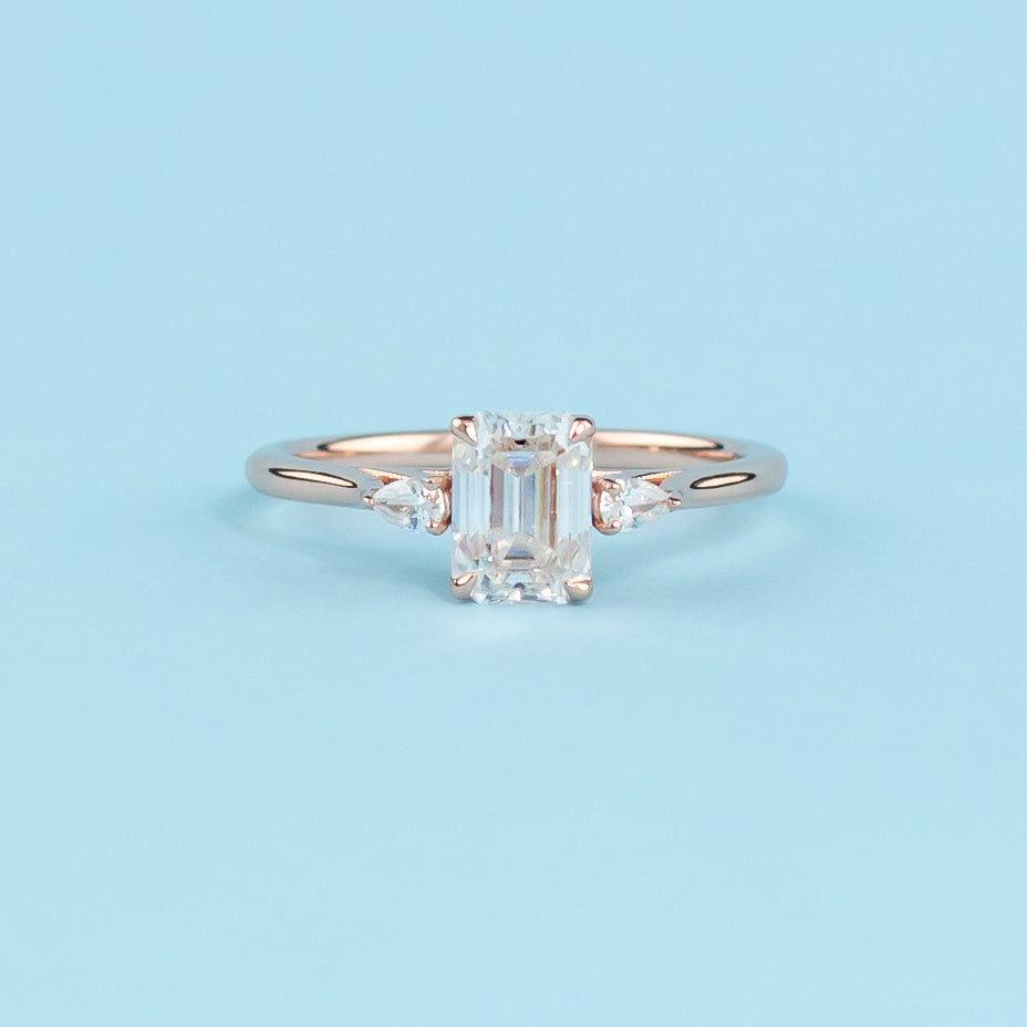 Stunning trilogy engagement ring with emerald cut moissanites, set in warm 9ct rose gold, symbolizing infinite love.