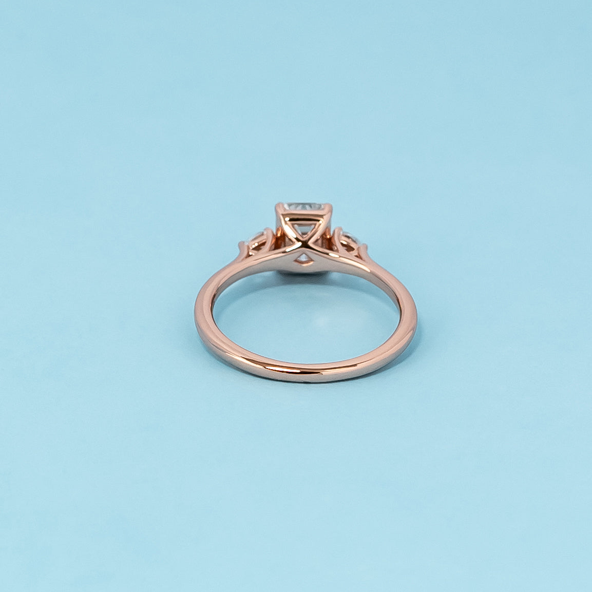 Luxurious 9ct rose gold engagement ring set featuring three beautiful emerald cut moissanites, representing enduring love.