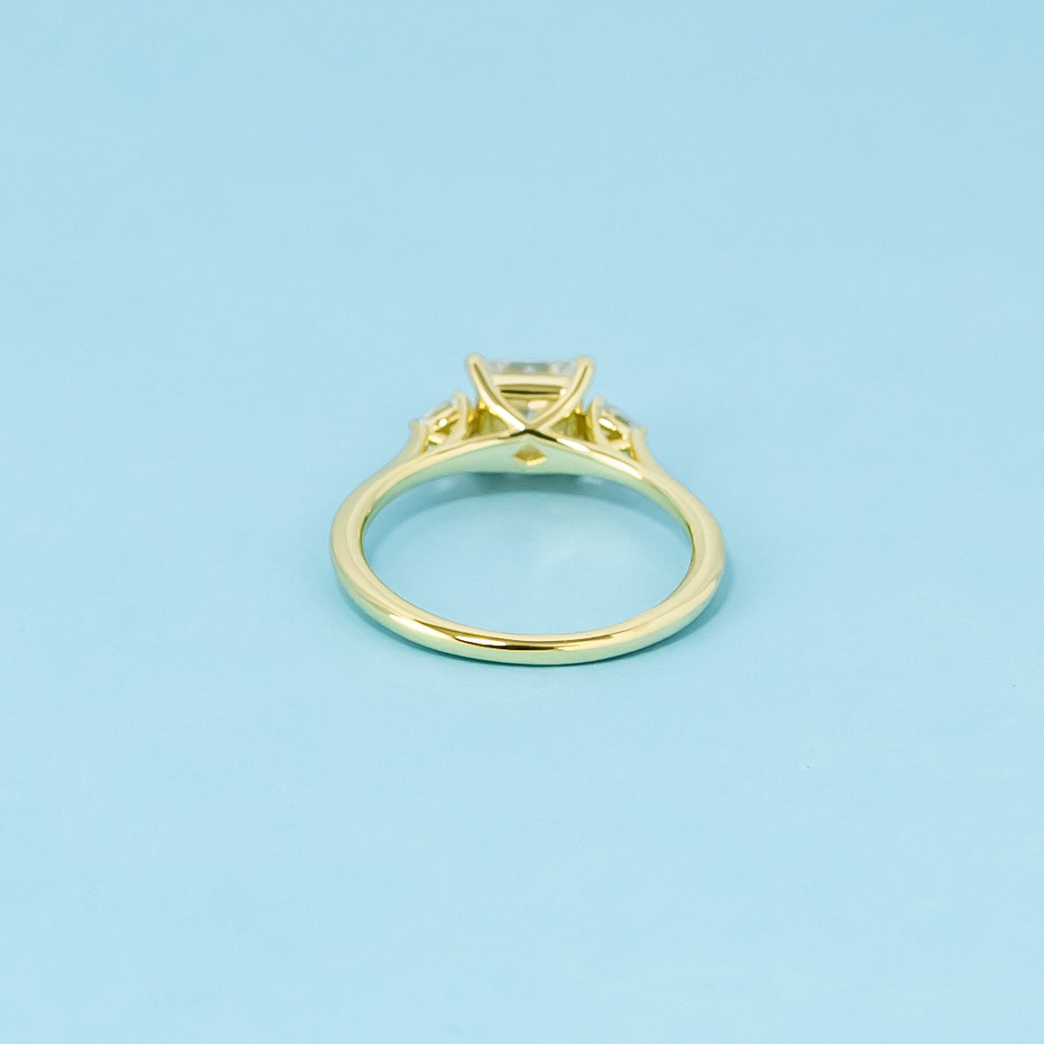 A classic trilogy ring with three brilliant princess cut moissanites set in a beautiful 9ct yellow gold band.