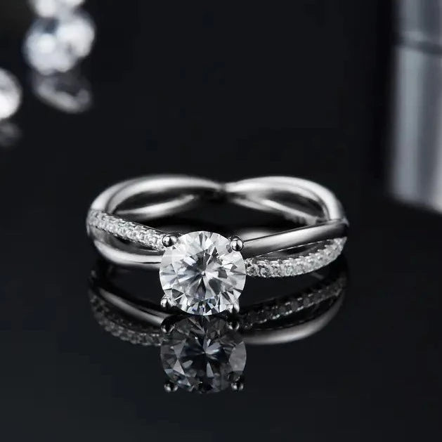 A detailed view of a sterling silver engagement ring, emphasizing the 1.00ct moissanite center stone and the intertwined design of the infinity band.