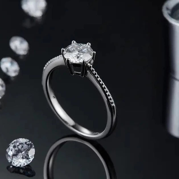 This sterling silver engagement ring offers a touch of vintage charm with its milgrain detailing and a secure 6-claw setting showcasing a brilliant 1.00ct moissanite.