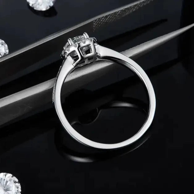This ring features a brilliant 0.50ct moissanite complemented by a halo of pave stones.
