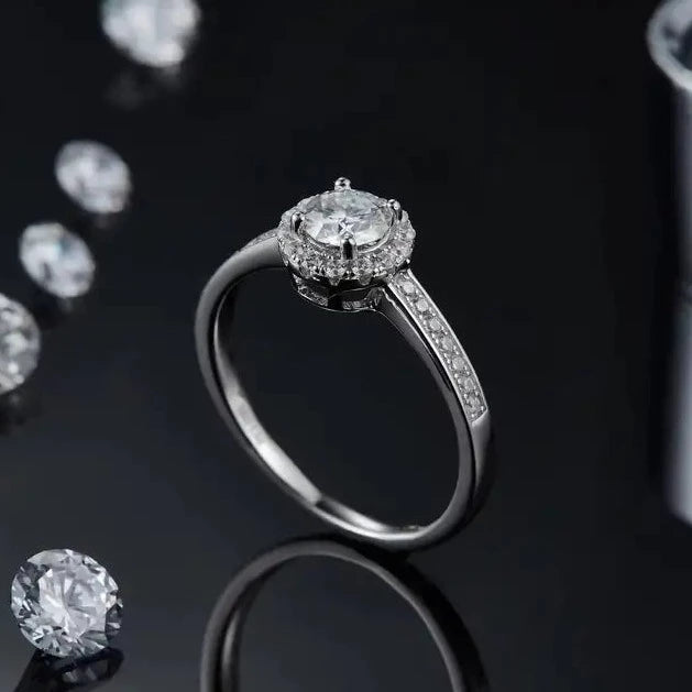 This 0.50ct moissanite engagement ring exudes luxury with its elegant pave halo setting in 9ct white gold.