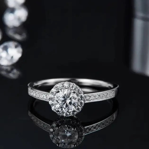 A refined engagement ring with a 0.50ct moissanite and a delicate pave halo, set in polished sterling silver for a timeless look.