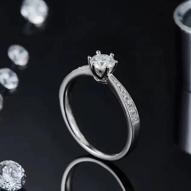 A classic 6 prong set 0.50 carat moissanite center stone, with small moissanite stones set into the rings band.