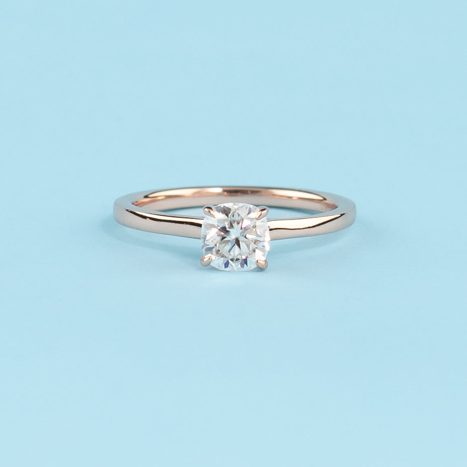 Elegant cushion cut moissanite engagement ring with a delicate hidden halo, set in warm 9ct rose gold.