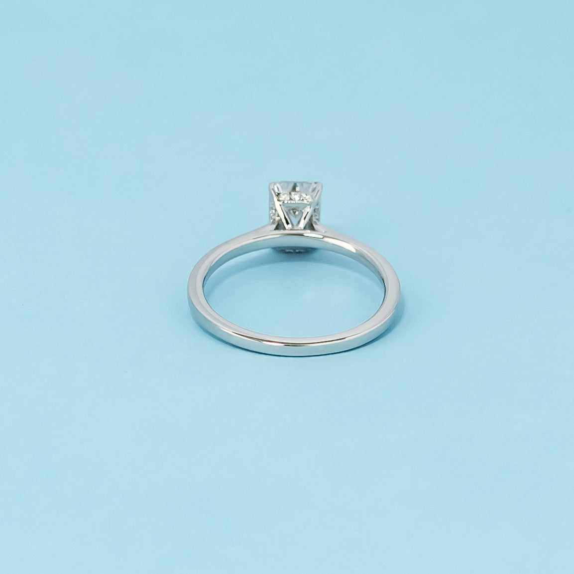Luxurious 9ct white gold engagement ring with a discreet hidden halo setting that enhances the brilliance of the emerald cut moissanite.
