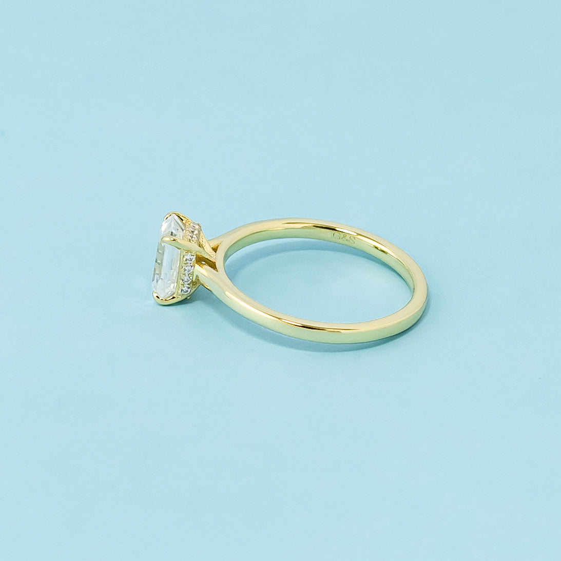 This 9ct yellow gold ring features a classic emerald cut moissanite with a hidden halo for a touch of surprise.