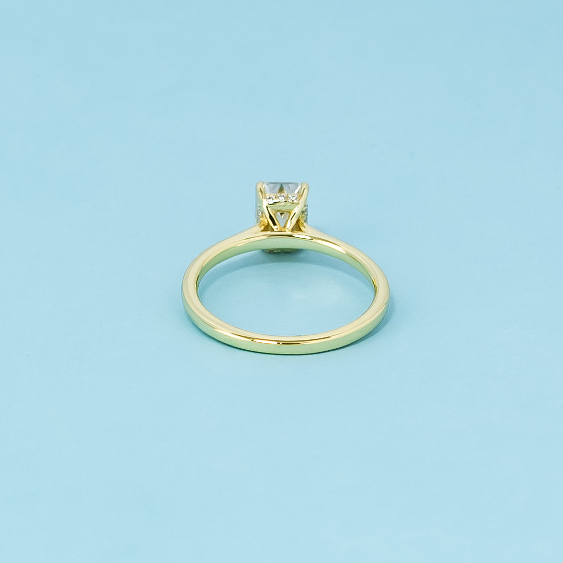 Indulge in the subtle luxury of this 9ct yellow gold ring, featuring an emerald cut moissanite with a discreet hidden halo.
