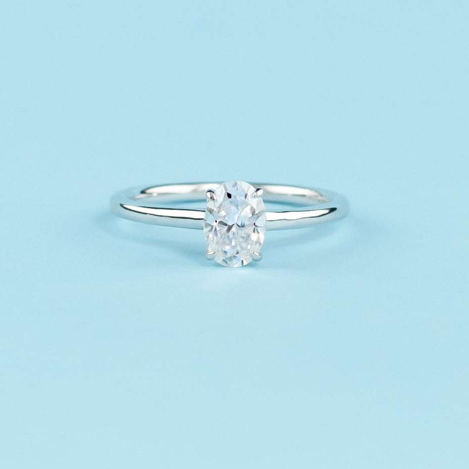 Elegant 9ct white gold engagement ring featuring an oval cut moissanite with a hidden halo for added brilliance.