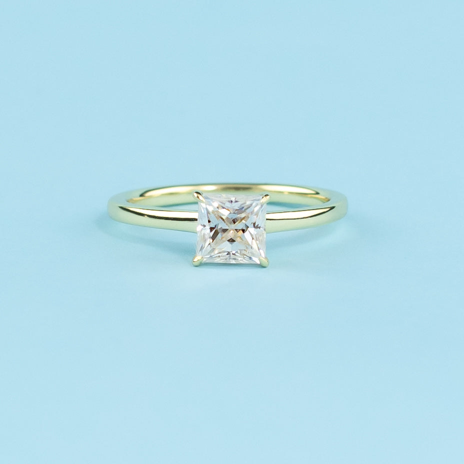 Discover the secret sparkle of this elegant ring with a hidden halo surrounding a brilliant princess cut moissanite.