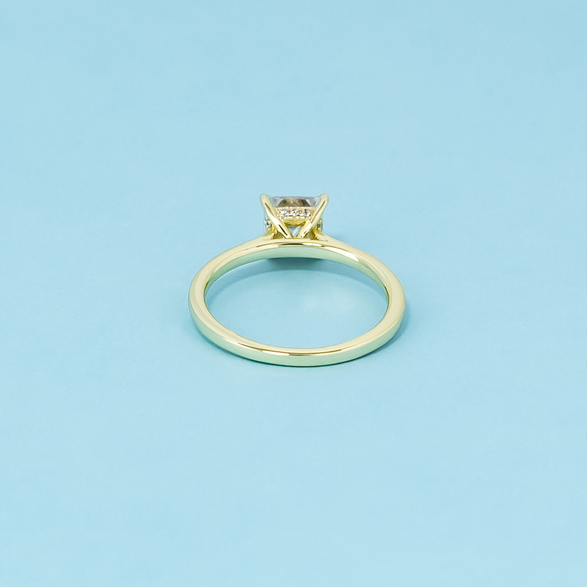 Indulge in the subtle luxury of this 9ct yellow gold ring, featuring a princess cut moissanite with a discreet hidden halo.