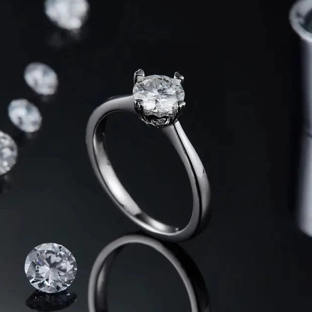 Close up of a 1.00ct Moissanite Engagement ring. Showing a sterling silver band, and heart shaped claws holding the large center stone.