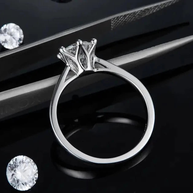 A 1.00ct moissanite shines in a unique 6-claw setting featuring a beautiful floral basket design, all in 9ct white gold.