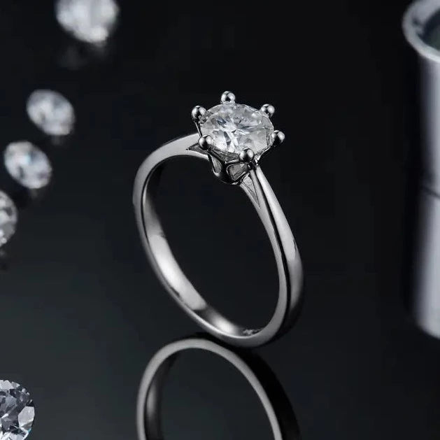 Close up of a 1.00ct Moissanite Engagement ring, displaying a sterling silver band and a floral basket design with six claws that delicately holds the centre stone.