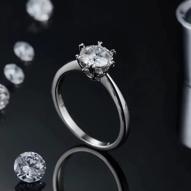 Close up of a 1.00ct Moissanite Engagement ring. Showing a sterling silver band, and heart shaped claws holding the large center stone.