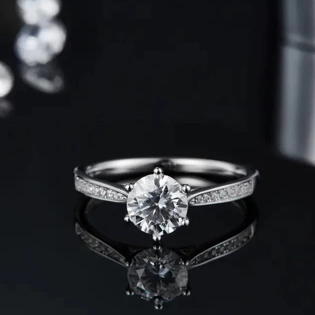 A beautiful engagement ring featuring a 1.00ct moissanite center stone and a tapered band embellished with pave-set moissanites, crafted in high-quality sterling silver.