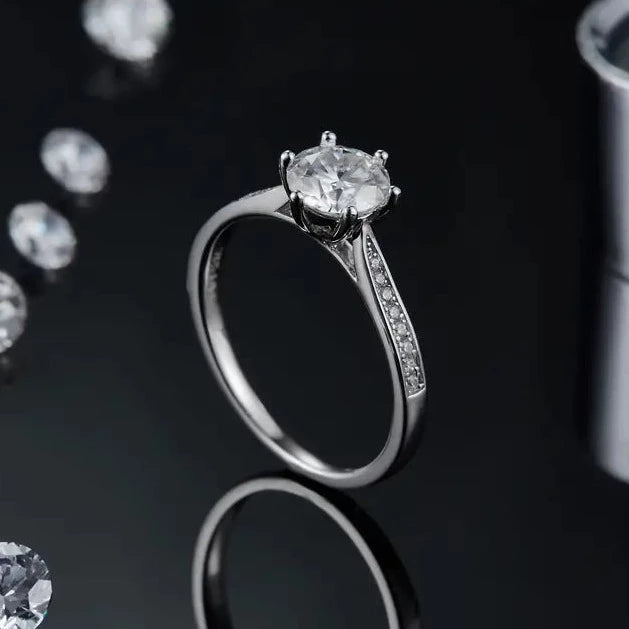 A sophisticated engagement ring with a 1.00ct moissanite center stone, set within a polished sterling silver band featuring a gracefully tapered pave setting.