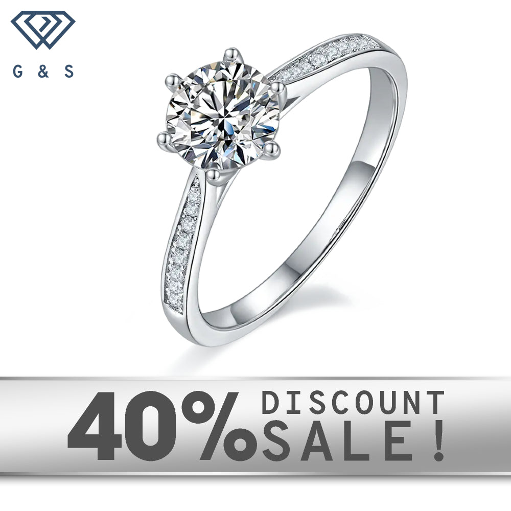 A 1.00ct moissanite center stone is highlighted by a delicate tapered pave setting on a 9ct white gold band.