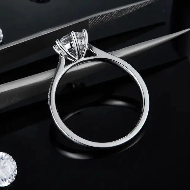 This ring features a brilliant 1.00ct moissanite complemented by a tapered band adorned with sparkling pave stones.