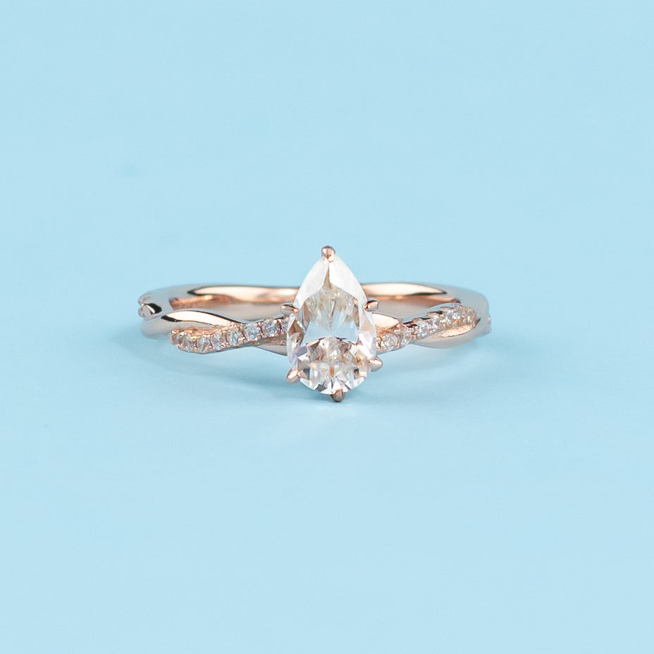 Elegant infinity engagement ring with a pear-shaped moissanite, set in warm 9ct rose gold.