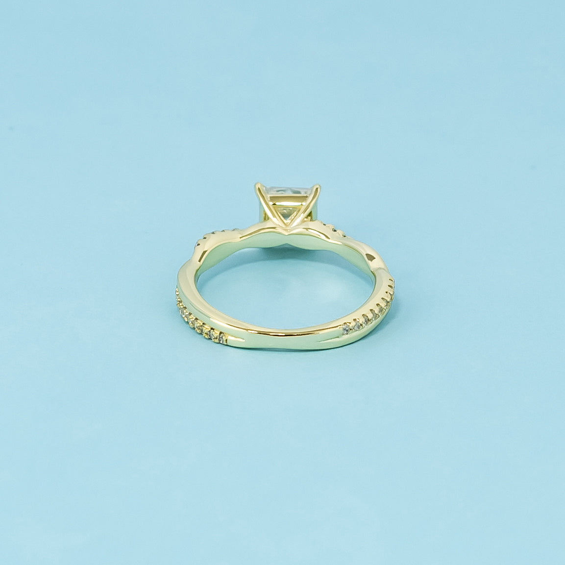 A symbol of everlasting love, this 9ct yellow gold ring features a princess cut moissanite and a flowing infinity design.