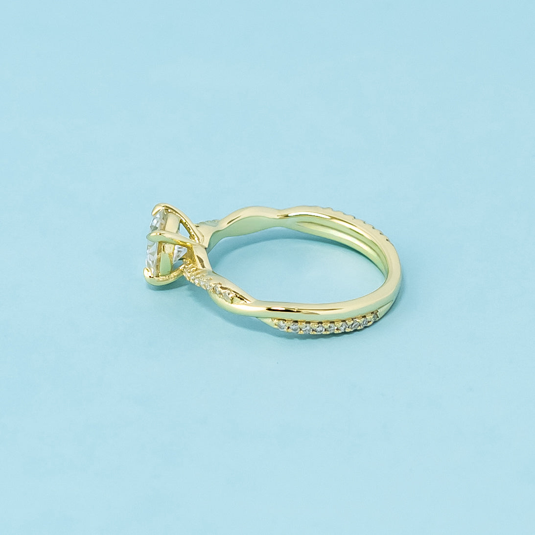 This 9ct yellow gold ring features a classic round brilliant moissanite with a delicate infinity design element.