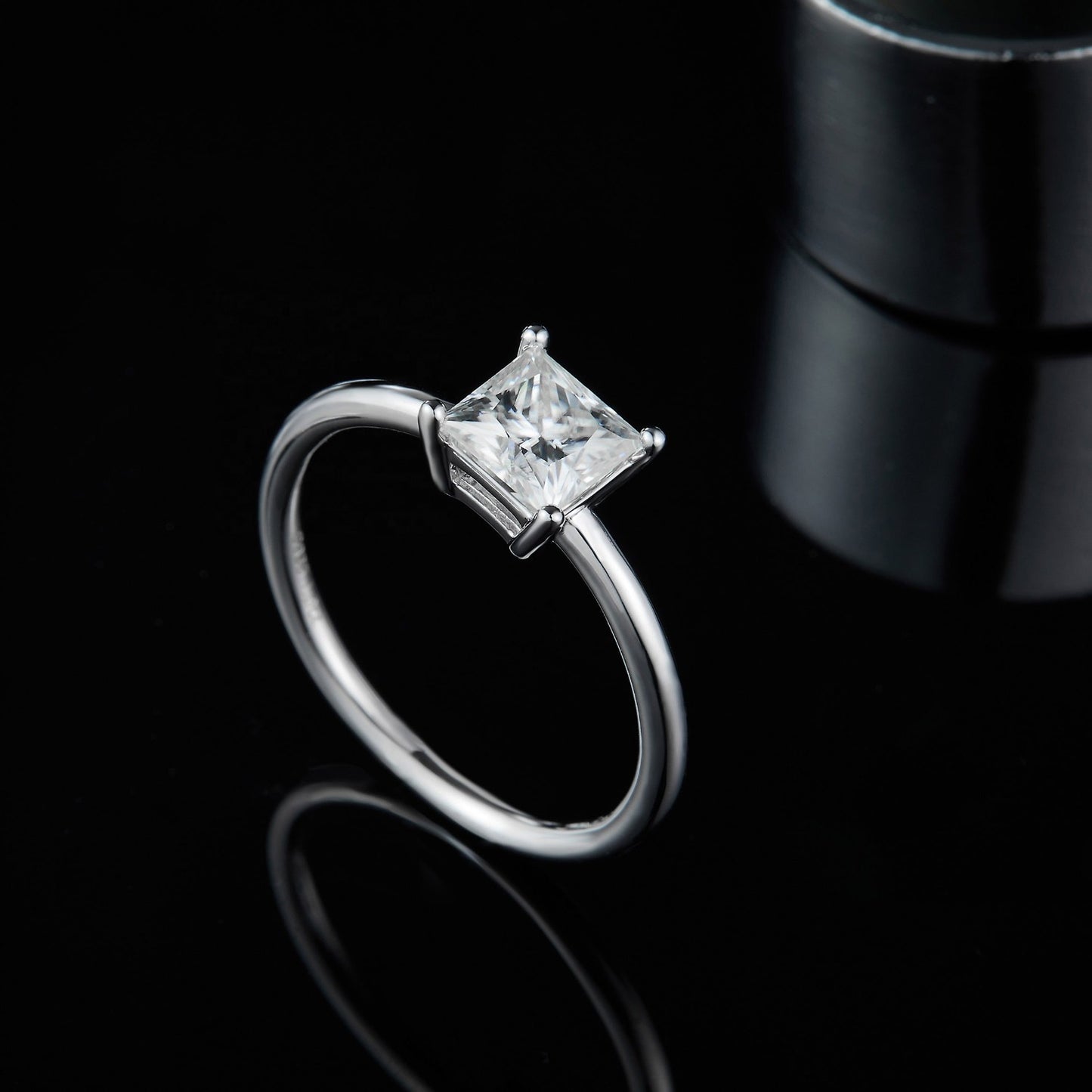 A sparkling princess cut moissanite takes center stage in this simple yet stunning sterling silver solitaire engagement ring.