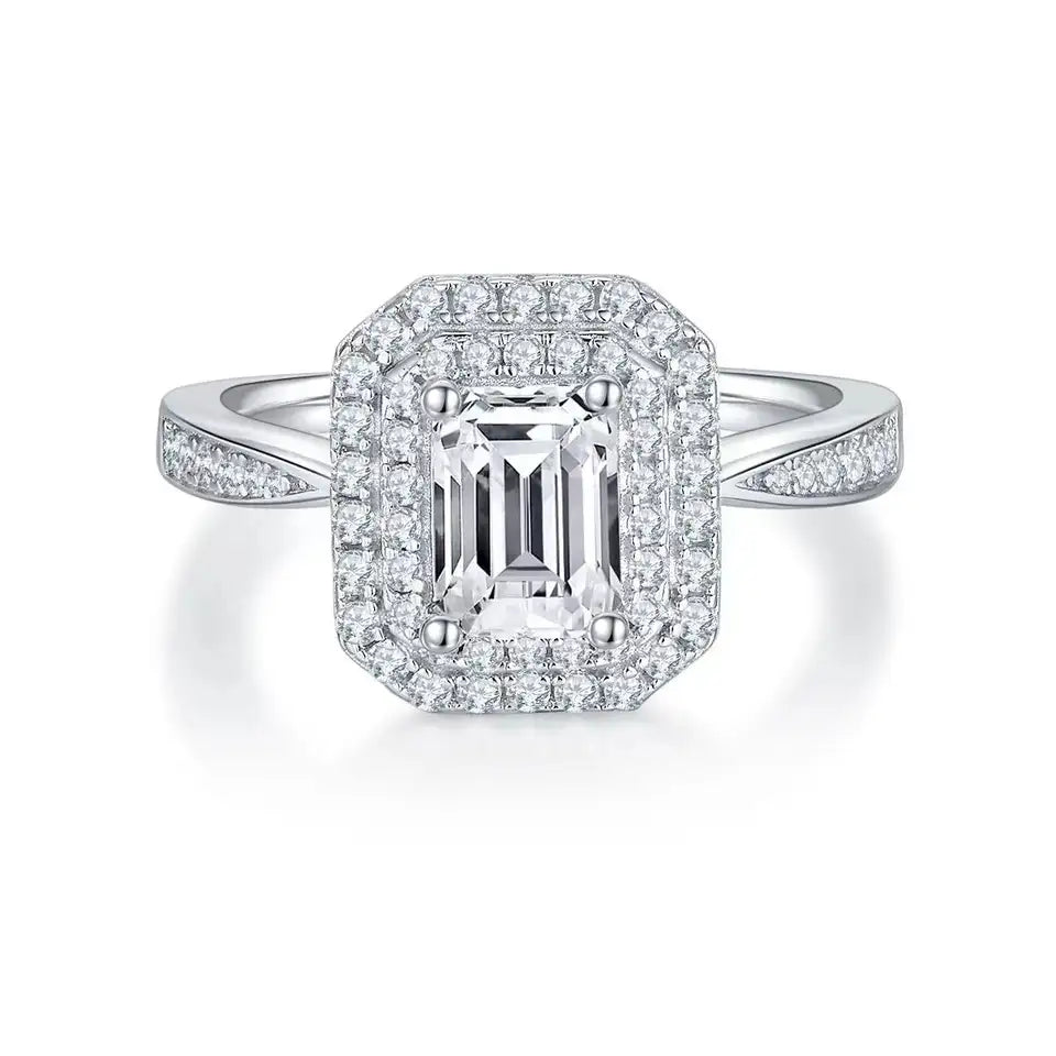 This ring features a brilliant emerald cut moissanite center stone encased in a double halo design.
