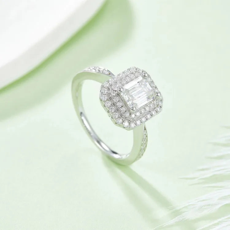 This ring features a unique double halo design surrounding a stunning emerald cut moissanite.