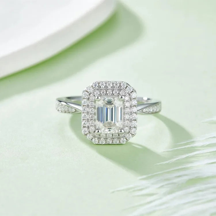A 1.00ct emerald cut moissanite encircled by two rows of pave-set stones, creating a double halo effect.