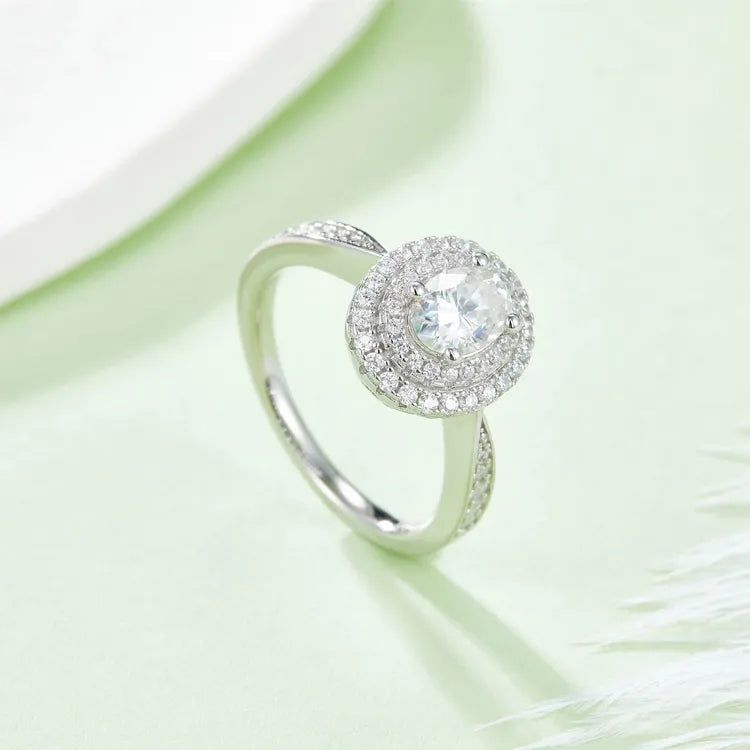This exquisite ring features a classic oval cut moissanite center stone and a unique double halo design.