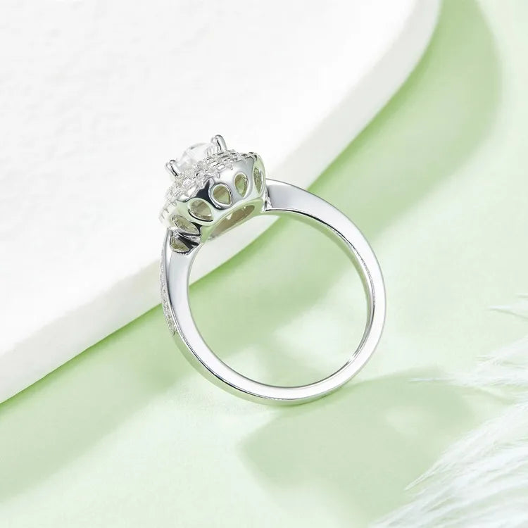 A side view of the ring, showing the profile of the pear-shaped moissanite and the layered halos.
