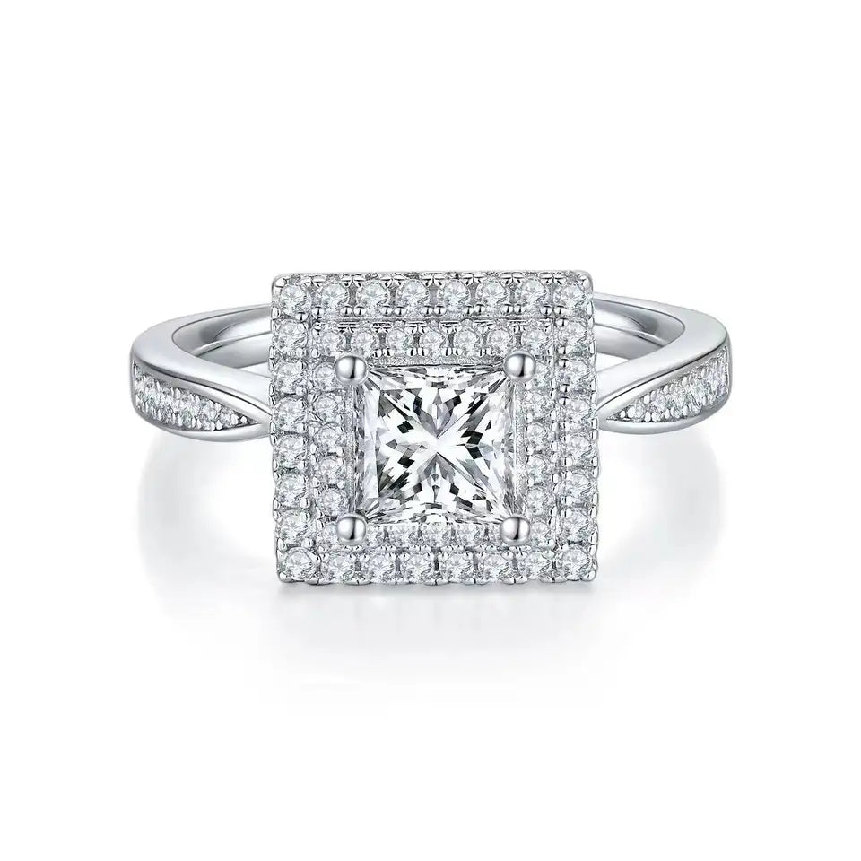 This ring showcases a brilliant princess cut moissanite center stone, accentuated by two dazzling halos.