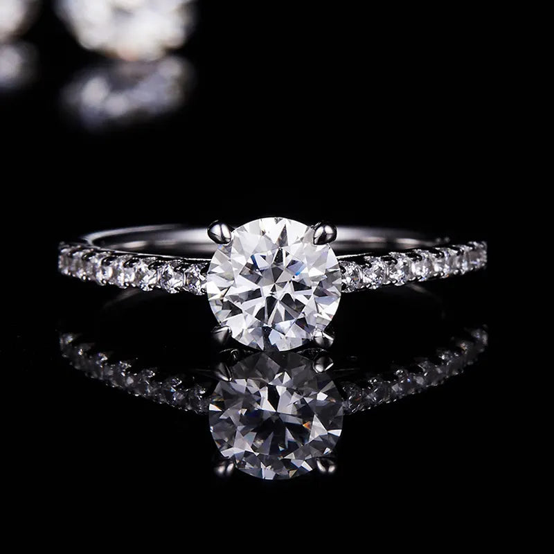 A close-up view of this sterling silver engagement ring reveals a 1.00ct round brilliant moissanite, exhibiting exceptional sparkle and fire, set in a detailed setting that enhances its brilliance.