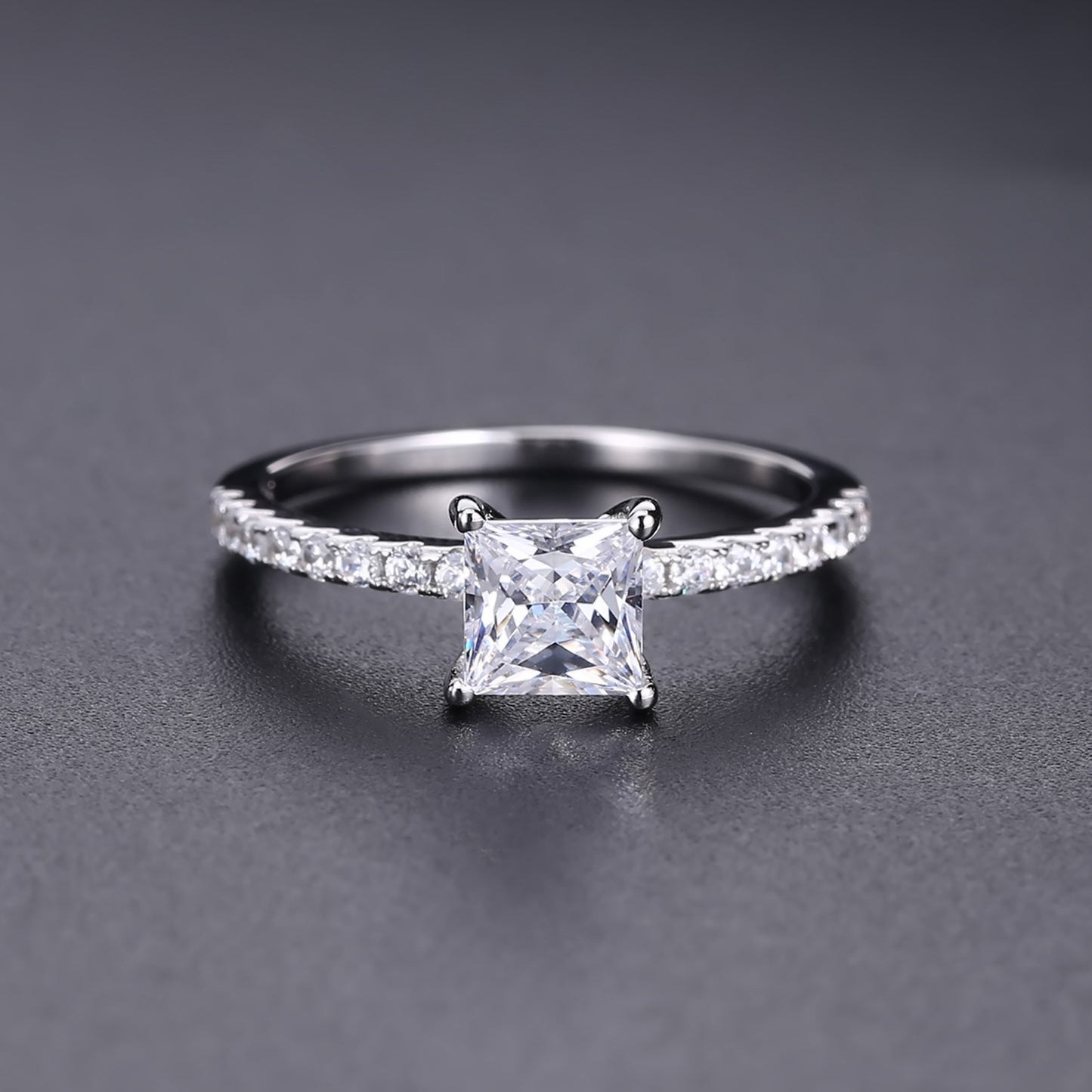 This sterling silver ring showcases a stunning 1.20ct princess cut moissanite as its focal point, perfect for a timeless proposal.