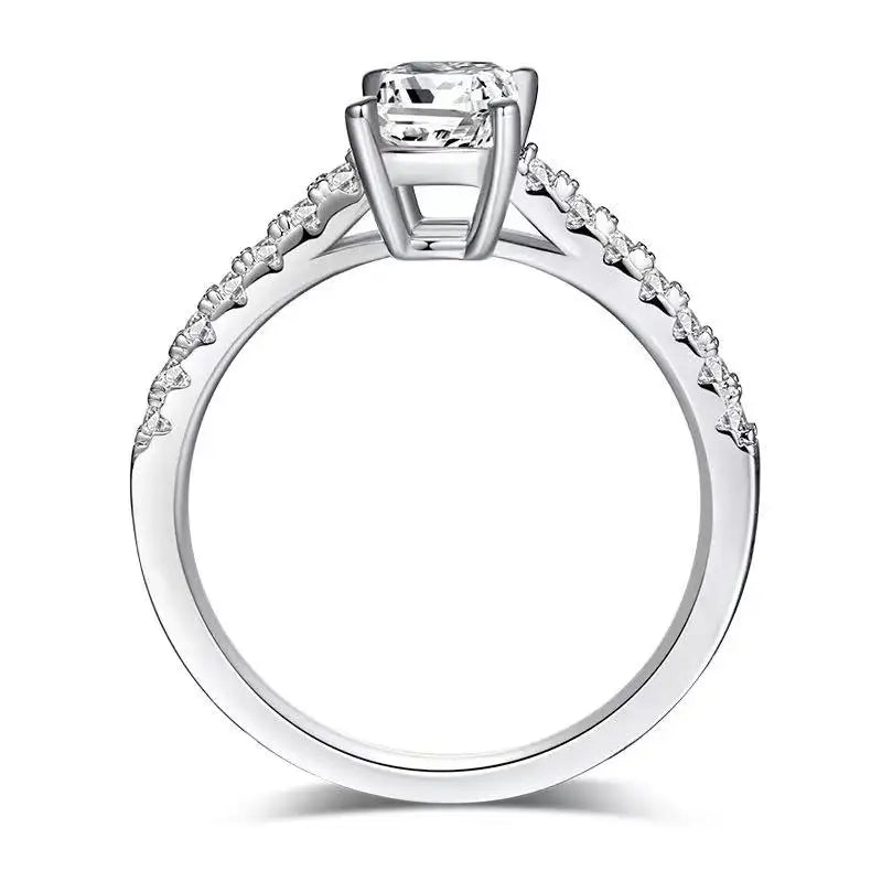 A timeless solitaire engagement ring with a 1.00ct emerald cut moissanite, secured by delicate basket prongs.